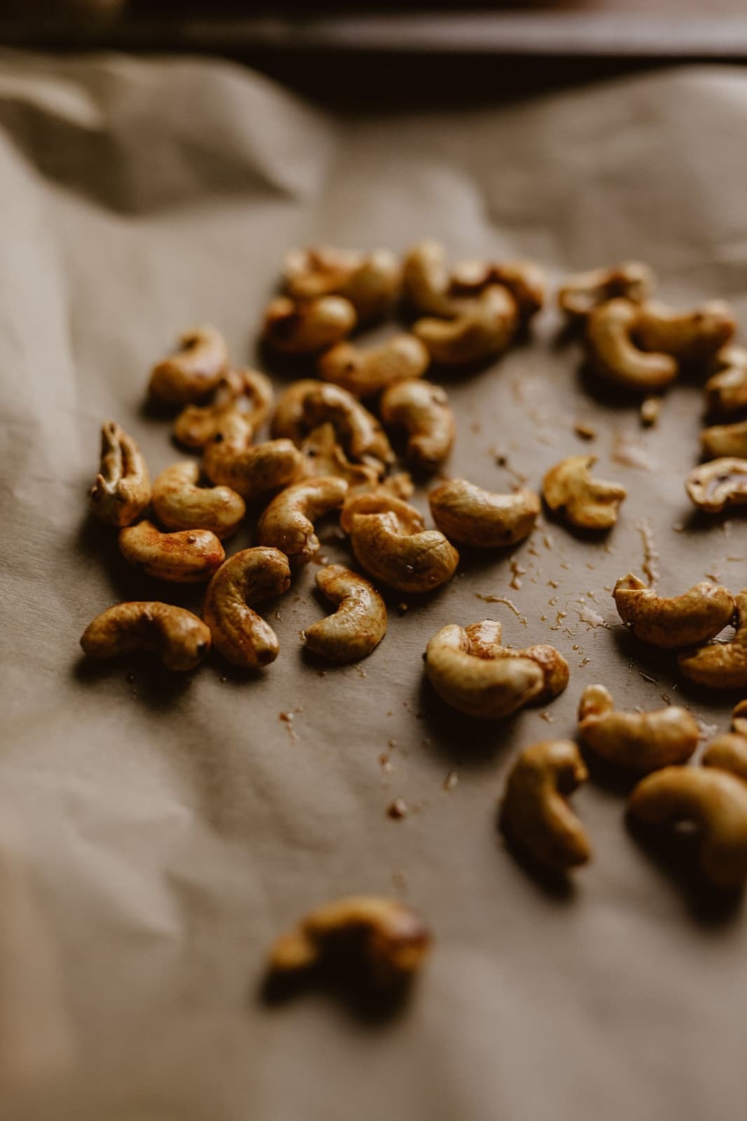 Cashew kernels roasted with a honey and spice coating on baking paper