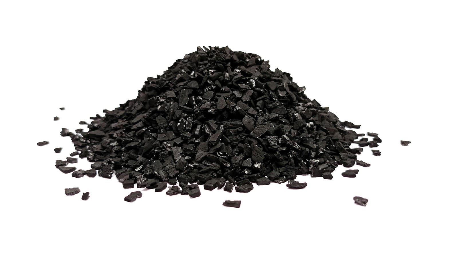 Montón de pequeños gránulos de carbón negro sobre fondo blanco