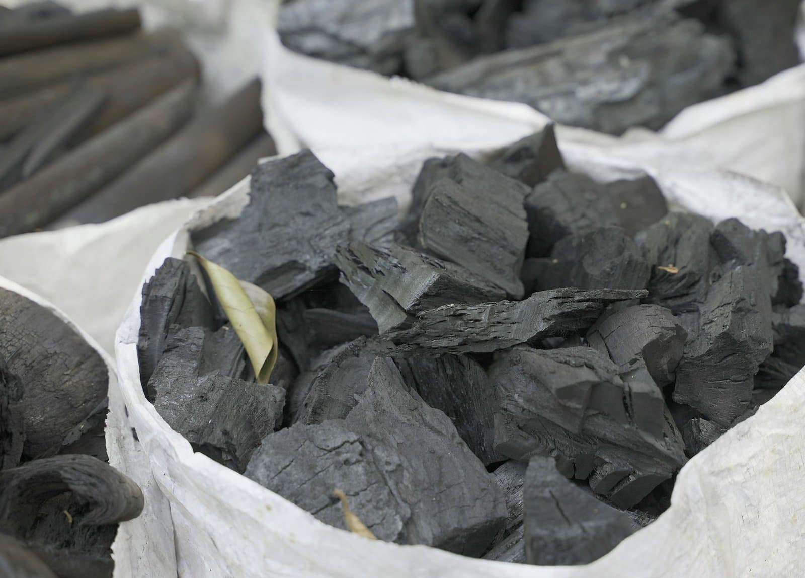 Pedaços de carvão preto em sacos de ráfia brancos
