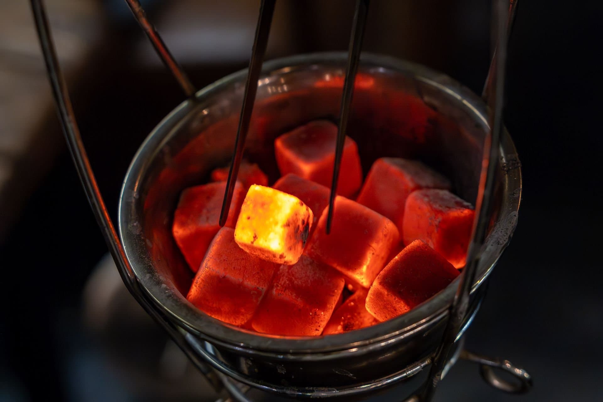 Glowing 25 mm charcoal cubes in a metal coal basket