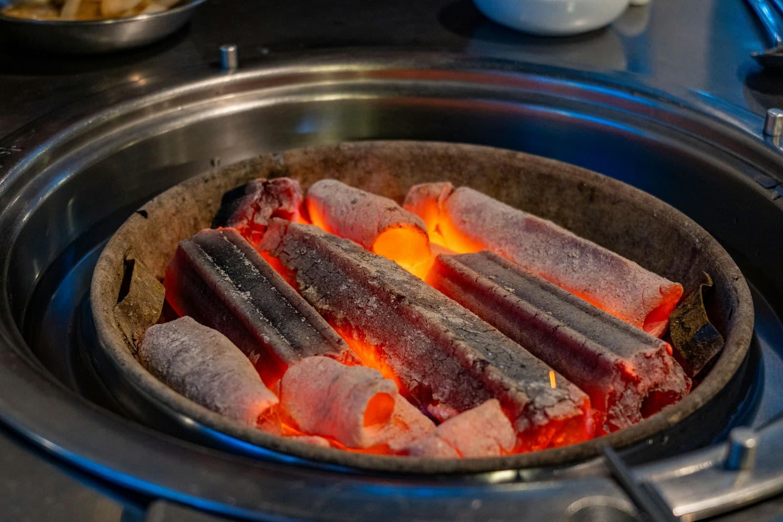Extruded charcoal briquette sticks glowing in a round tabletop grill