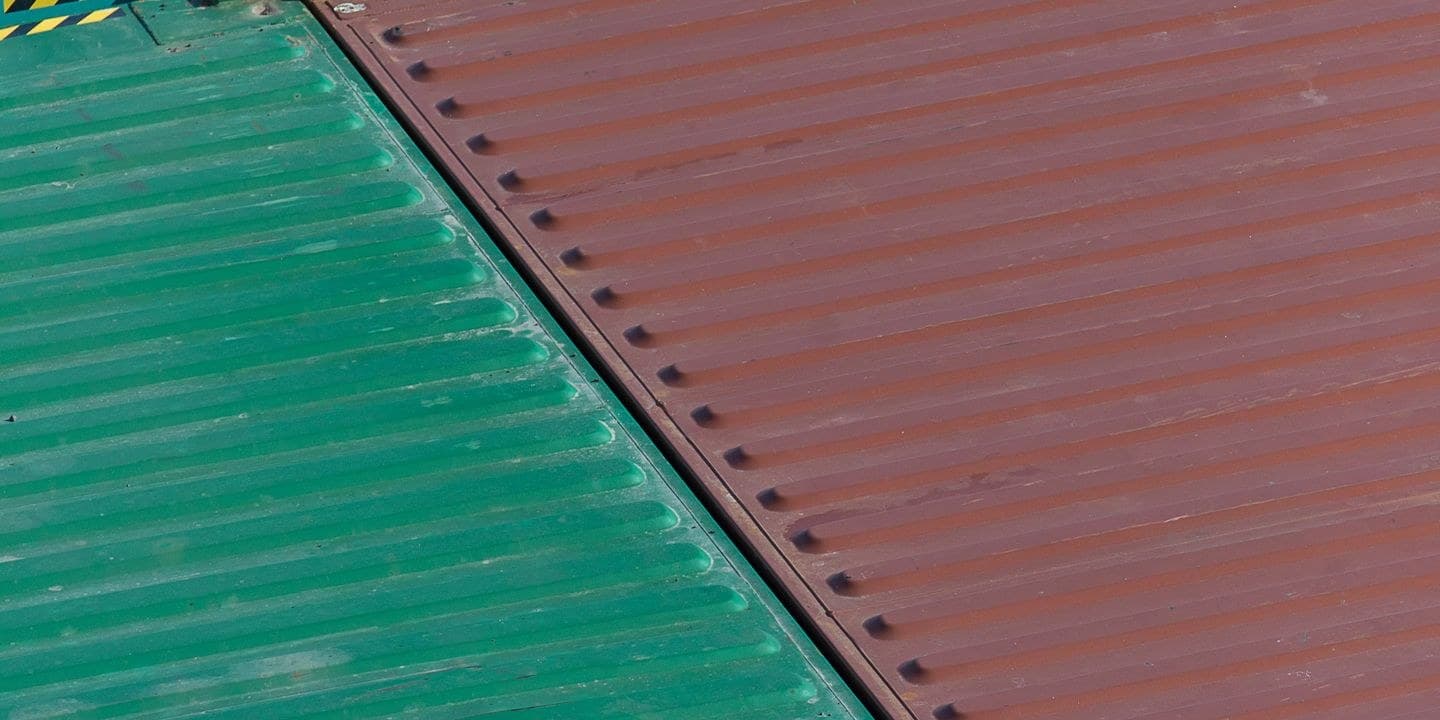 Corrugated steel roofs of two shipping containers, one green and one brown